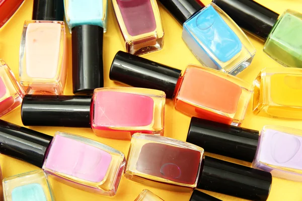 Group of bright nail polishes, on yellow background — Stock Photo, Image