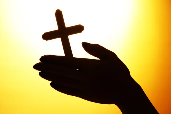 Vrouwelijke handen met kruisbeeld, op gele achtergrond — Stockfoto