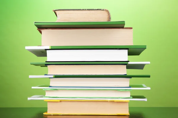 Stapel interessante boeken en de tijdschriften op houten tafel op groene achtergrond — Stockfoto