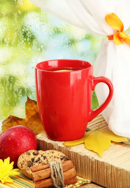 Cup of hot tea and autumn leaves, on rain background — Stock Photo, Image