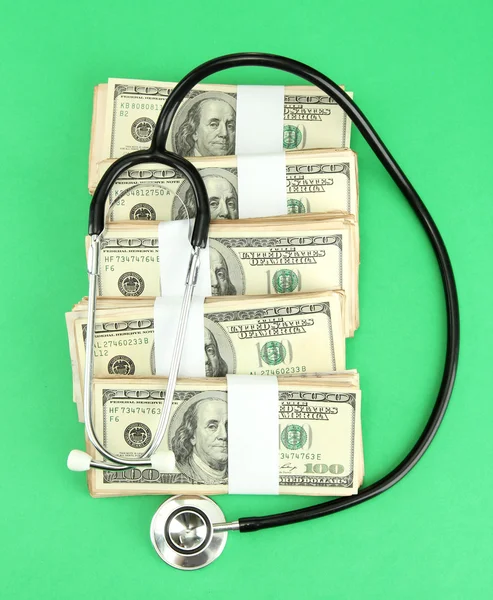 Conceito de custo de cuidados de saúde: estetoscópio e dólares em fundo verde — Fotografia de Stock
