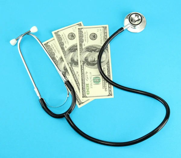 Concepto de coste sanitario: estetoscopio y dólares sobre fondo azul — Foto de Stock