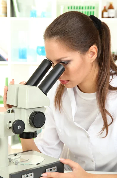 Mladý vědec dívá do mikroskopu v laboratoři — Stock fotografie