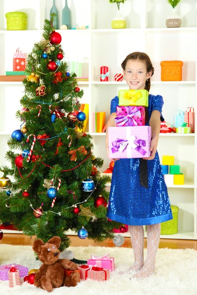 Kleines Mädchen hält Geschenkbox in der Nähe des Weihnachtsbaums — Stockfoto