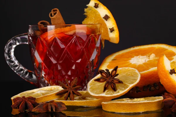 Fragrant mulled wine in glass with spices and oranges around on purple background — Stock Photo, Image