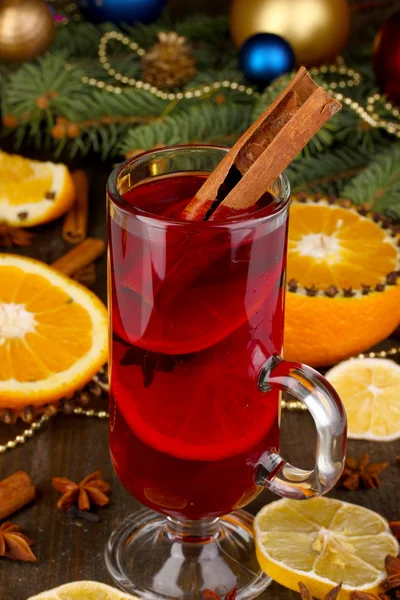 Fragrant mulled wine in glass with spices and oranges around on wooden table — Stock Photo, Image