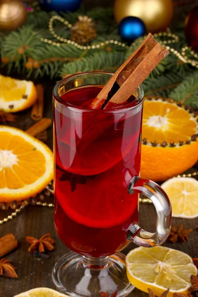 Vino caliente fragante en vaso con especias y naranjas en la mesa de madera —  Fotos de Stock