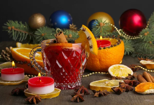 Geurige glühwein in glas met specerijen en sinaasappelen rond op houten tafel — Stockfoto