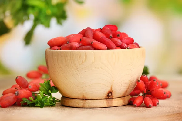 Olgun barberries masada yeşil yaprakları ile ahşap kase — Stok fotoğraf