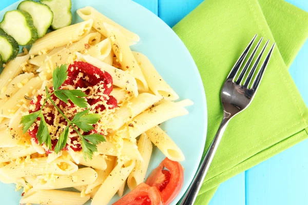 Piatto di pasta rigatoni con salsa di pomodoro sul tavolo di legno blu da vicino — Foto Stock