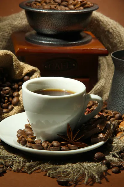 Kopp kaffe, kvarn, turk och kaffebönor på brun bakgrund — Stockfoto