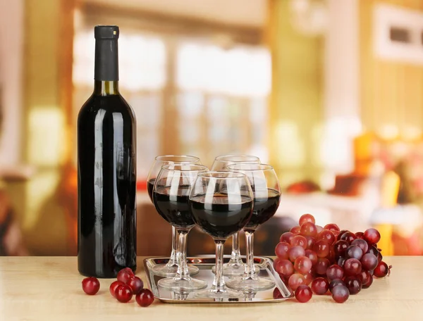 Červené víno ve sklenici a láhev na pozadí místnosti — Stock fotografie