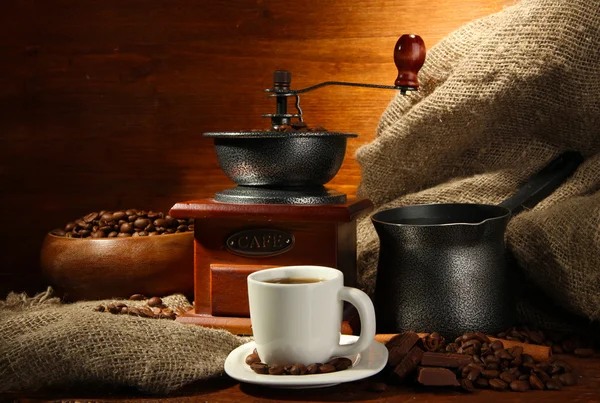 Coffee grinder, turk and cup of coffee on brown wooden background — Stock Photo, Image