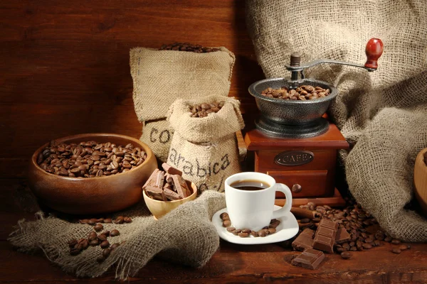 Młynek do kawy i filiżanka kawy na brązowym drewnianym tle — Zdjęcie stockowe