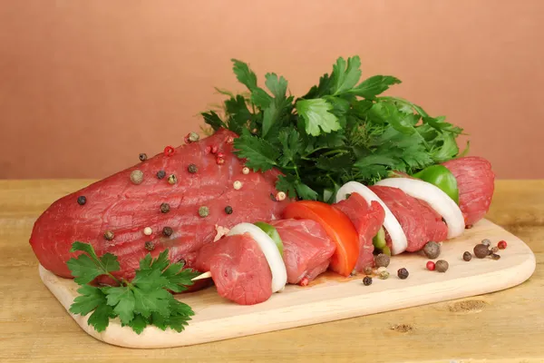 Surowy wołowiny marynowane z ziół i przypraw na drewnianym stole na brązowym tle — Zdjęcie stockowe