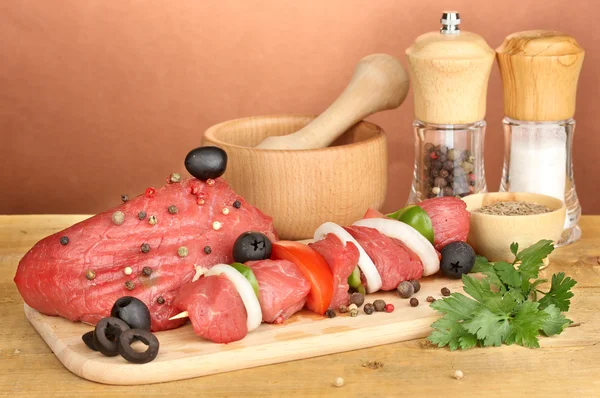 Carne di manzo cruda marinata con erbe e spezie su tavolo di legno su sfondo marrone — Foto Stock
