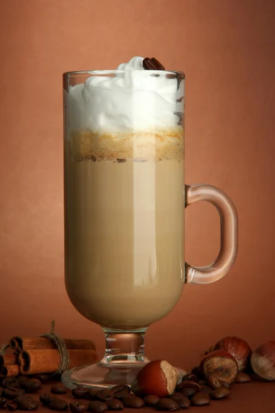 Latte de café perfumado em copo de vidro com especiarias, em fundo marrom — Fotografia de Stock