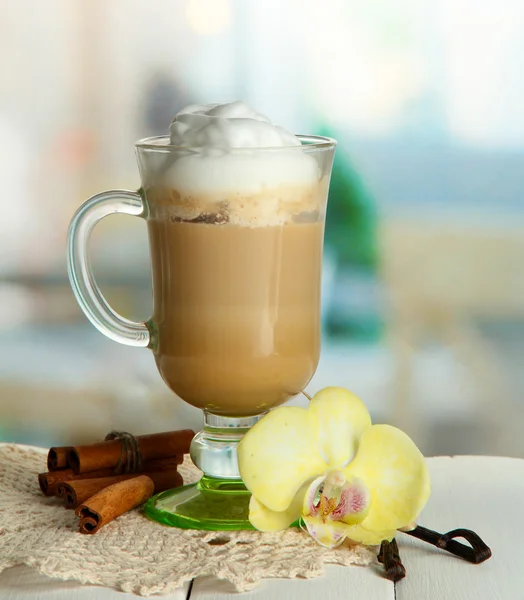 Latte de café perfumado em copo de vidro com especiarias, na mesa de madeira — Fotografia de Stock