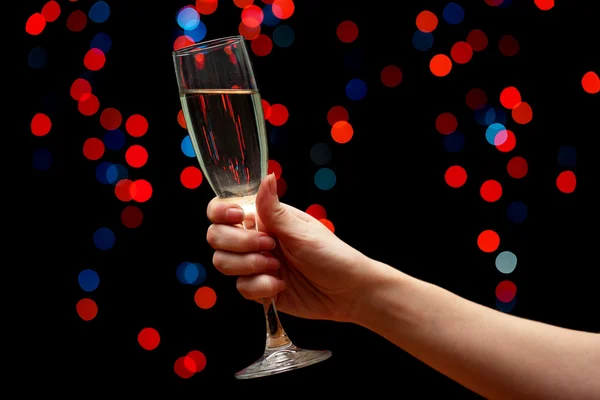 Женская рука с бокалом шампанского, на фоне гирлянды — стоковое фото