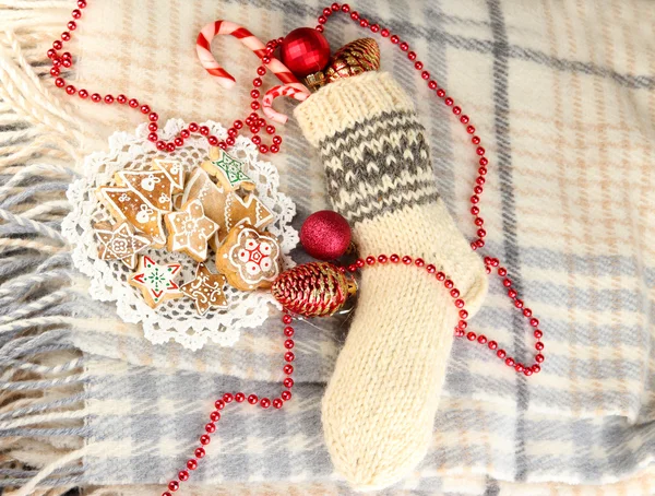 Warm knitted sock with gifts on plaid close-up — Stock Photo, Image