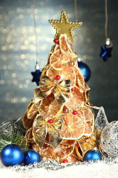 Beau sapin de Noël de citrons secs avec décor, sur fond bleu brillant — Photo