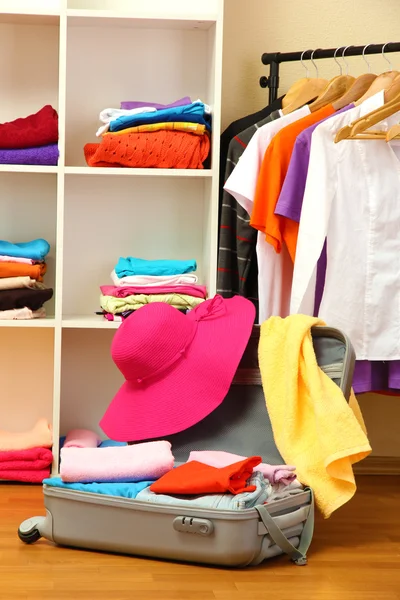 Open silver suitcase with clothing in room — Stock Photo, Image