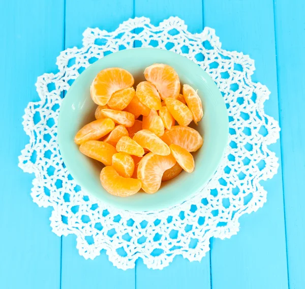 Tasty mandarine's slices on color plate on blue background — Stock Photo, Image