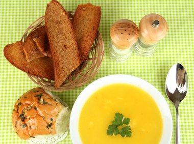 Yeşil masa örtüsü üzerinde beyaz tabak içinde kokulu çorba