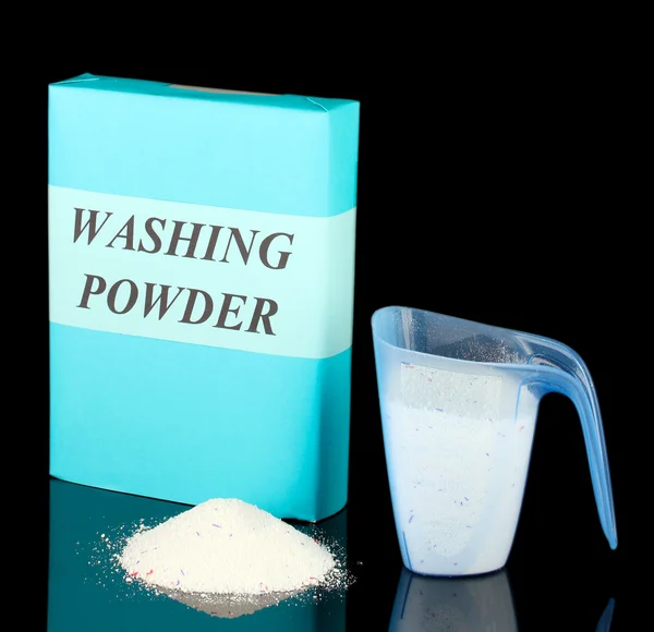 Box of washing powder with blue measuring cup, isolated on black — Stock Photo, Image