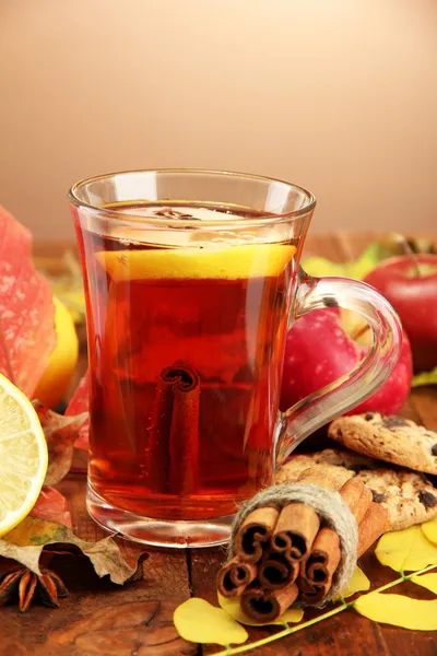 Tazza di tè caldo e foglie autunnali, su sfondo marrone — Foto Stock