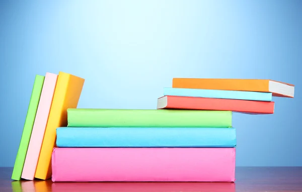Pilha de livros multicoloridos sobre fundo azul — Fotografia de Stock
