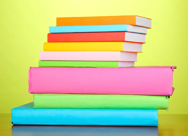 Stapel multicolor boeken op groene achtergrond — Stockfoto