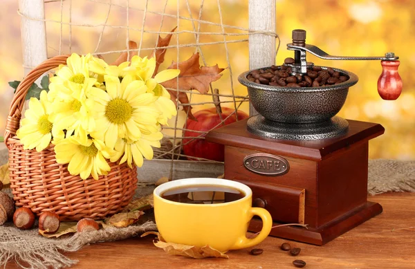 Composición otoñal: molinillo de café, flores y hojas sobre fondo brillante — Foto de Stock