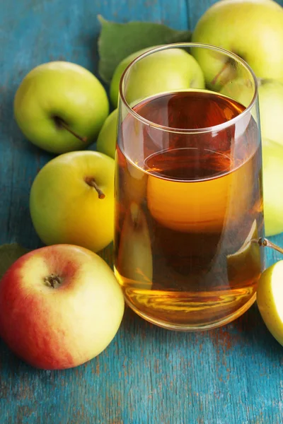 Useful apple juice with apples around on wooden table — Stock Photo, Image