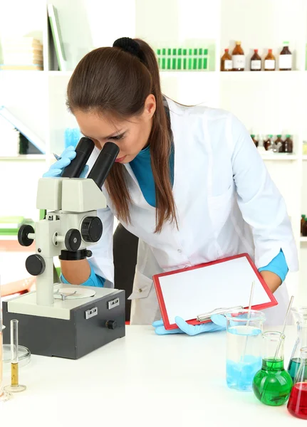 Unga forskare undersöker mikroskopet i laboratorium — Stockfoto