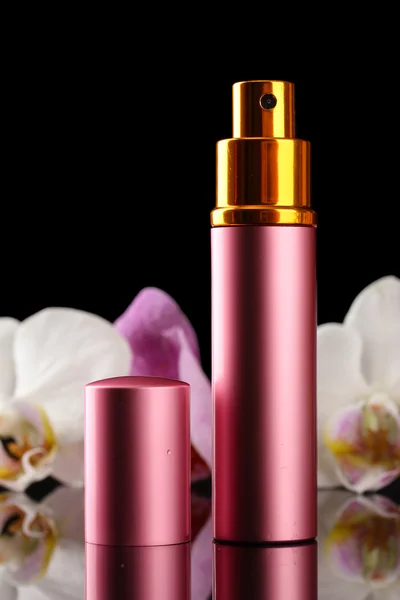 Women's perfume in beautiful bottle and orchid flowers, on black background — Stock Photo, Image