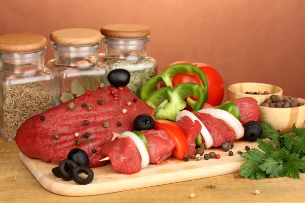 Raw beef meat marinated with herbs and spices on wooden table on brown background — Stock Photo, Image