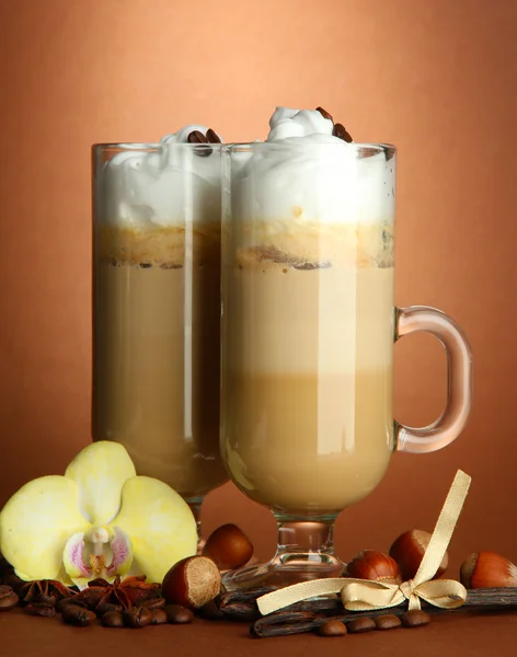 Ароматный кофе латте в стаканах со специями, на коричневом фоне — стоковое фото