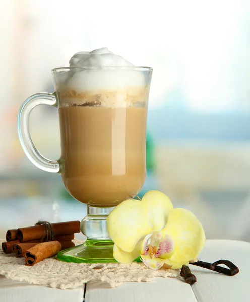 Latte de café perfumado em copo de vidro com especiarias, na mesa de madeira — Fotografia de Stock