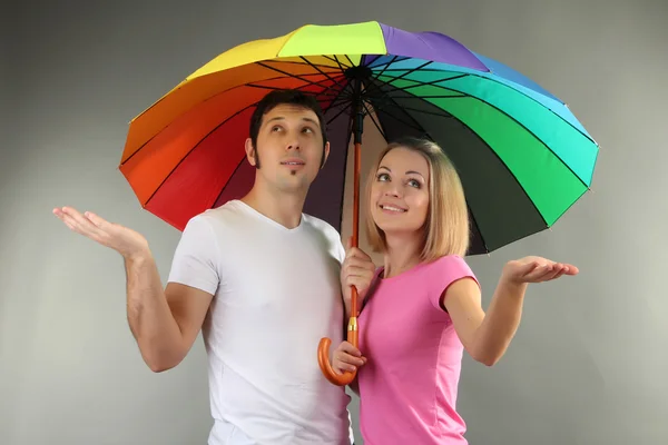 Casal amoroso com guarda-chuva no fundo cinza — Fotografia de Stock