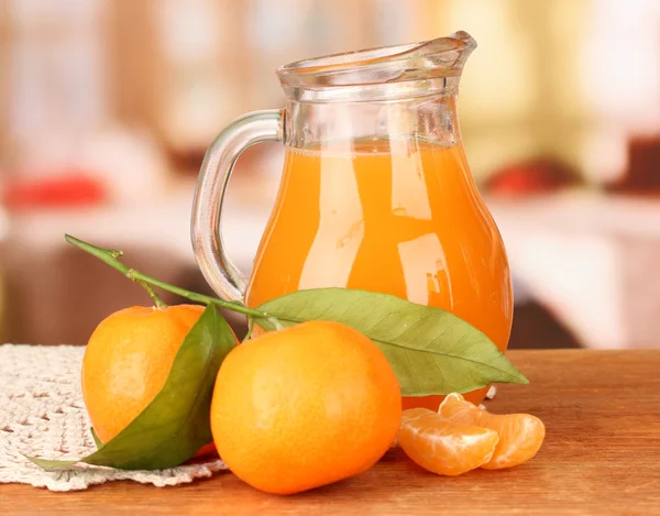 Full jug of tangerine juice, on wooden table on bright background — Stock Photo, Image