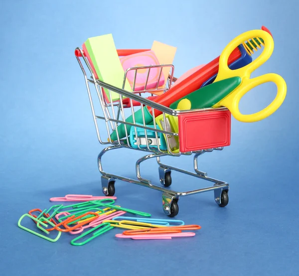 Trolley with school equipment on blue background — Stock Photo, Image
