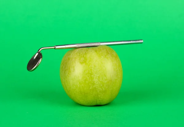 Green apple and dental tool on color background — Zdjęcie stockowe