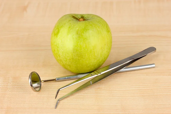 Green apple and dental tools on wooden background — Zdjęcie stockowe