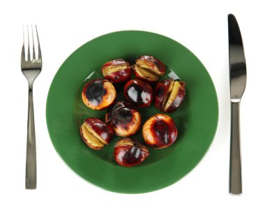 roasted chestnuts in the green plate with fork and knife isolated on white clipart
