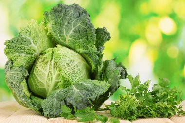 Fresh savoy cabbage on wooden table on natural background