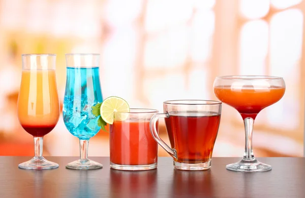 Several glasses of different drinks on bright background — Stock Photo, Image