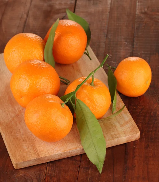 Sweet tangerines with leaves, on wooden background — Stock Photo, Image