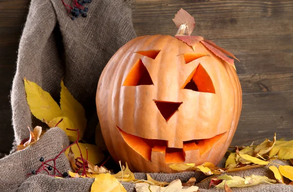 Zucca di Halloween e foglie autunnali, su sfondo di legno — Foto Stock