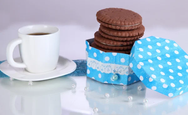 Choklad cookies med krämig skikt och kopp kaffe på lila bakgrund — Stockfoto